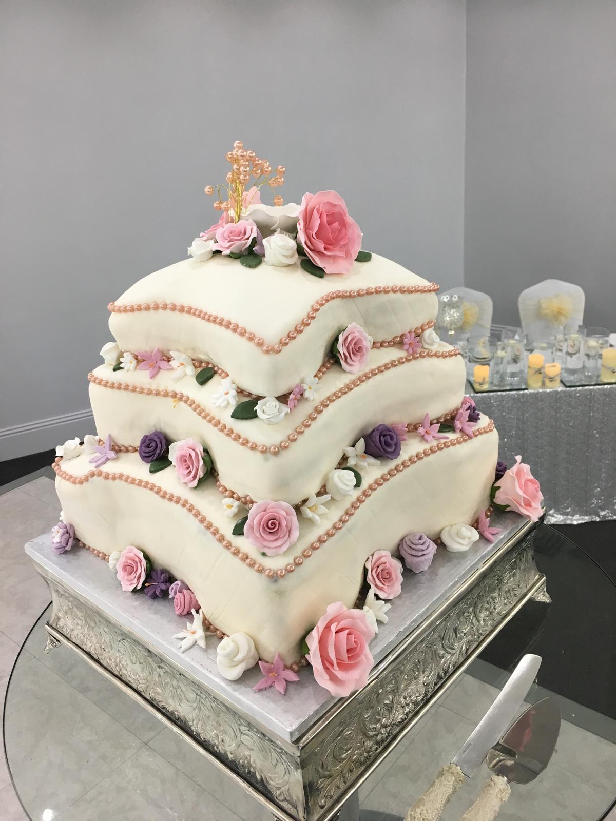 Decorative wedding cake with flowers on a reflective surface