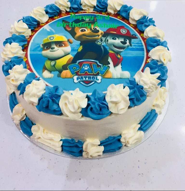 Paw Patrol birthday cake with blue and white frosting on a white surface.