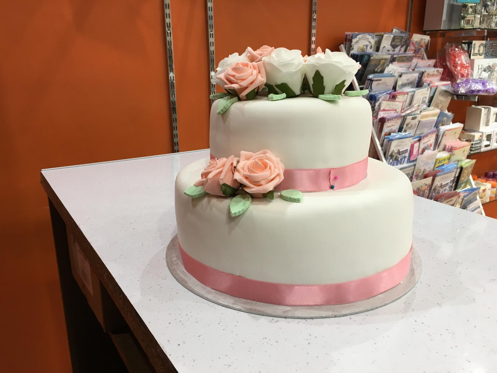 Two-tiered cake with floral decorations on a white surface.