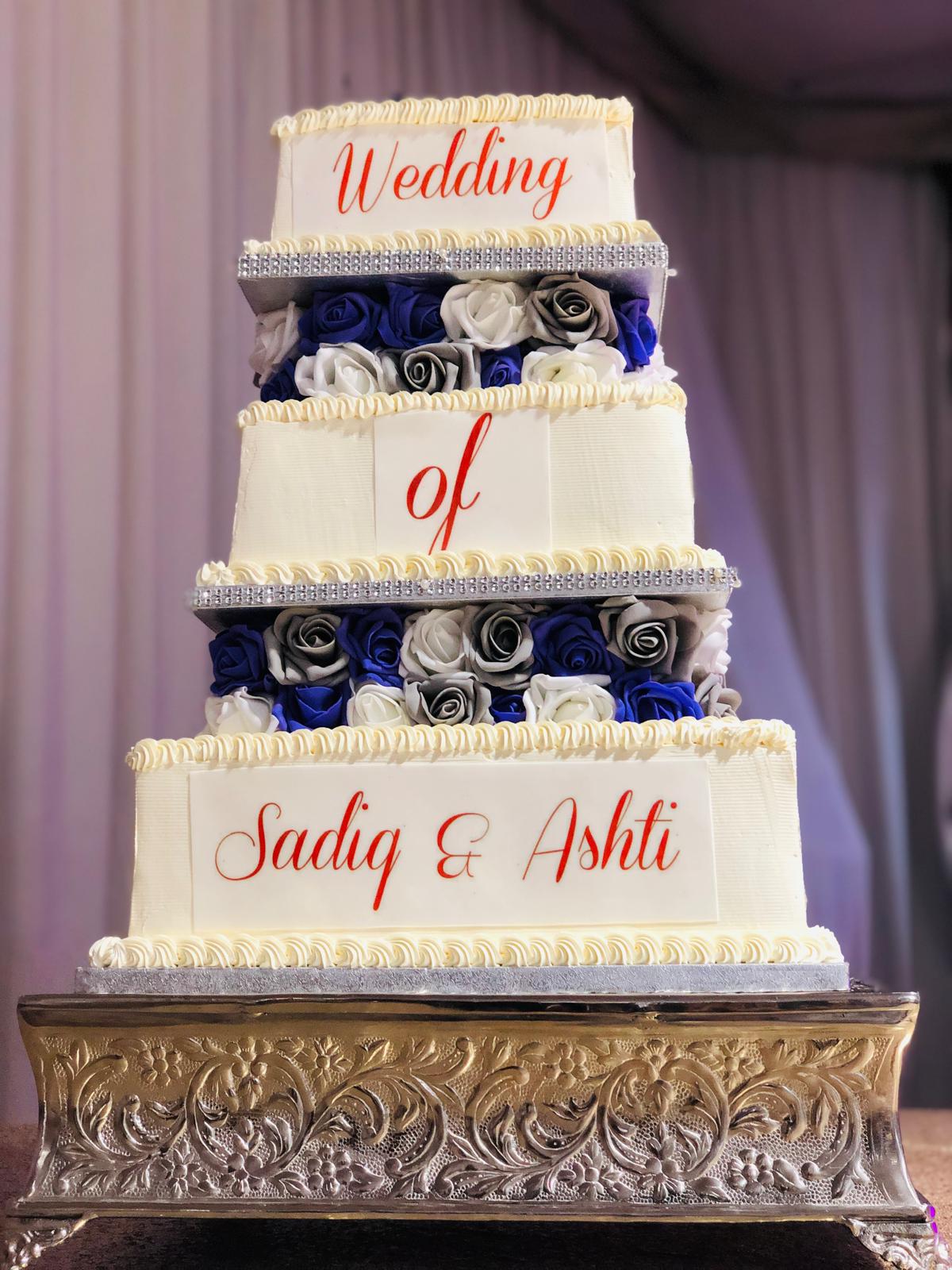Four-tiered wedding cake with blue and white flowers.
