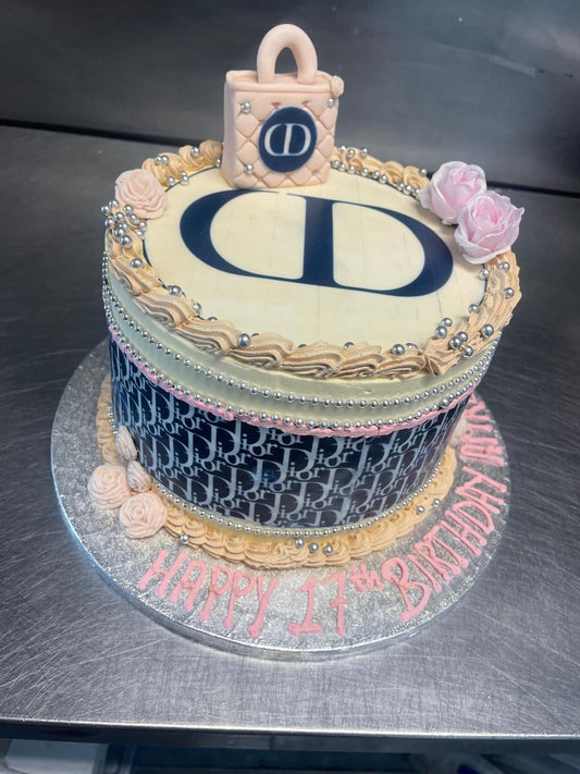 Decorative cake with 'D' initials and 'Happy 14th Birthday' text on a metallic surface.
